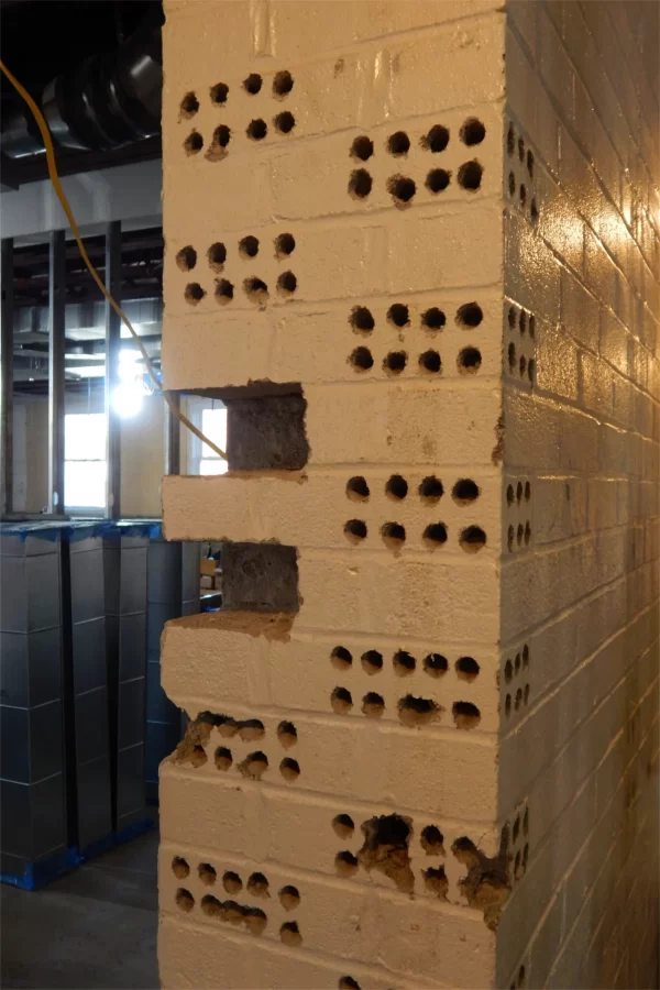 Masonry toothing in progress. Two bricks have been removed from this doorway, forming "tooths" — not teeth. Others have been drilled preparatory to chiseling them out. (Doug Hubley/Bates College)