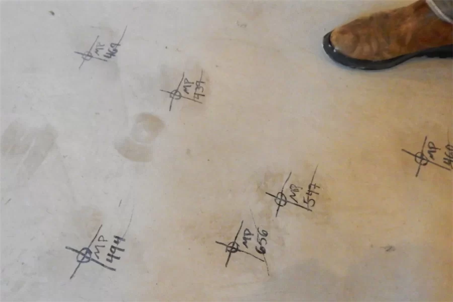 A laser pointer placed on these marks will guide workers as they install utility hardware on the ceiling. The boot belongs to Bates construction administrator Jacob Kendall. (Doug Hubley/Bates College)