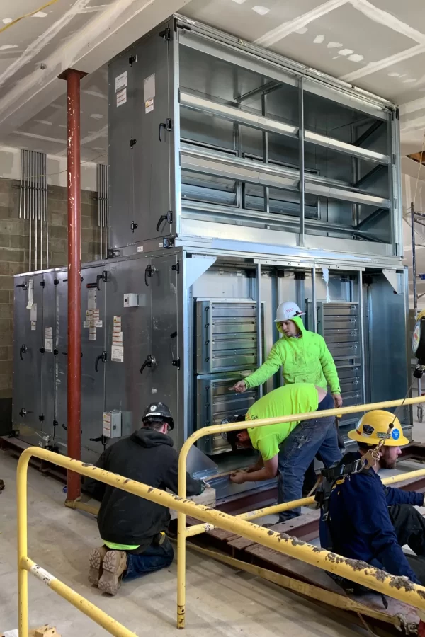 Workers tend to a just-installed section of Dana Chemistry Hall’s new air handler. The building's elevator shaft is shown at left. (Jacob Kendall/Bates College)