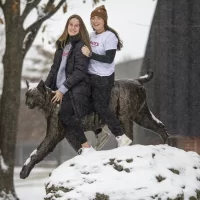 Anna Cote ’25 of Auburn, Maine, and Emily Gianunzio ’22 of Darien, Conn., pose on and by the Bates Bobcat.They are field hockey teammates this year; last year, Gianunzio, on a one-year leave from Bates because of the pandemic, coached Cote when the latter was a senior at St. Dom’s.