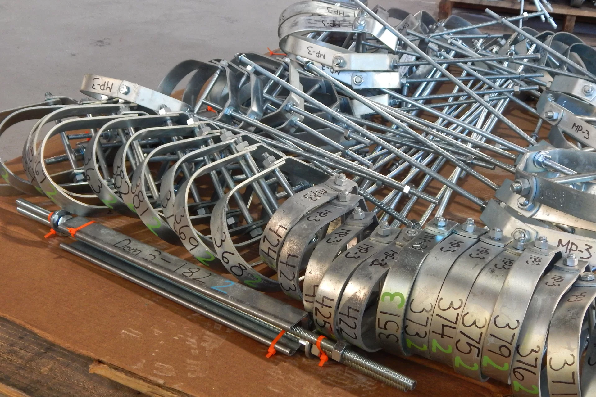 Hangers for utility infrastructure sit on a pallet awaiting installation at certain points designated by the markings. They will hang from the threaded rods, which have been cut to specified lengths so that several pipe or conduit runs can be “stacked” in a given space. (Doug Hubley/Bates College)