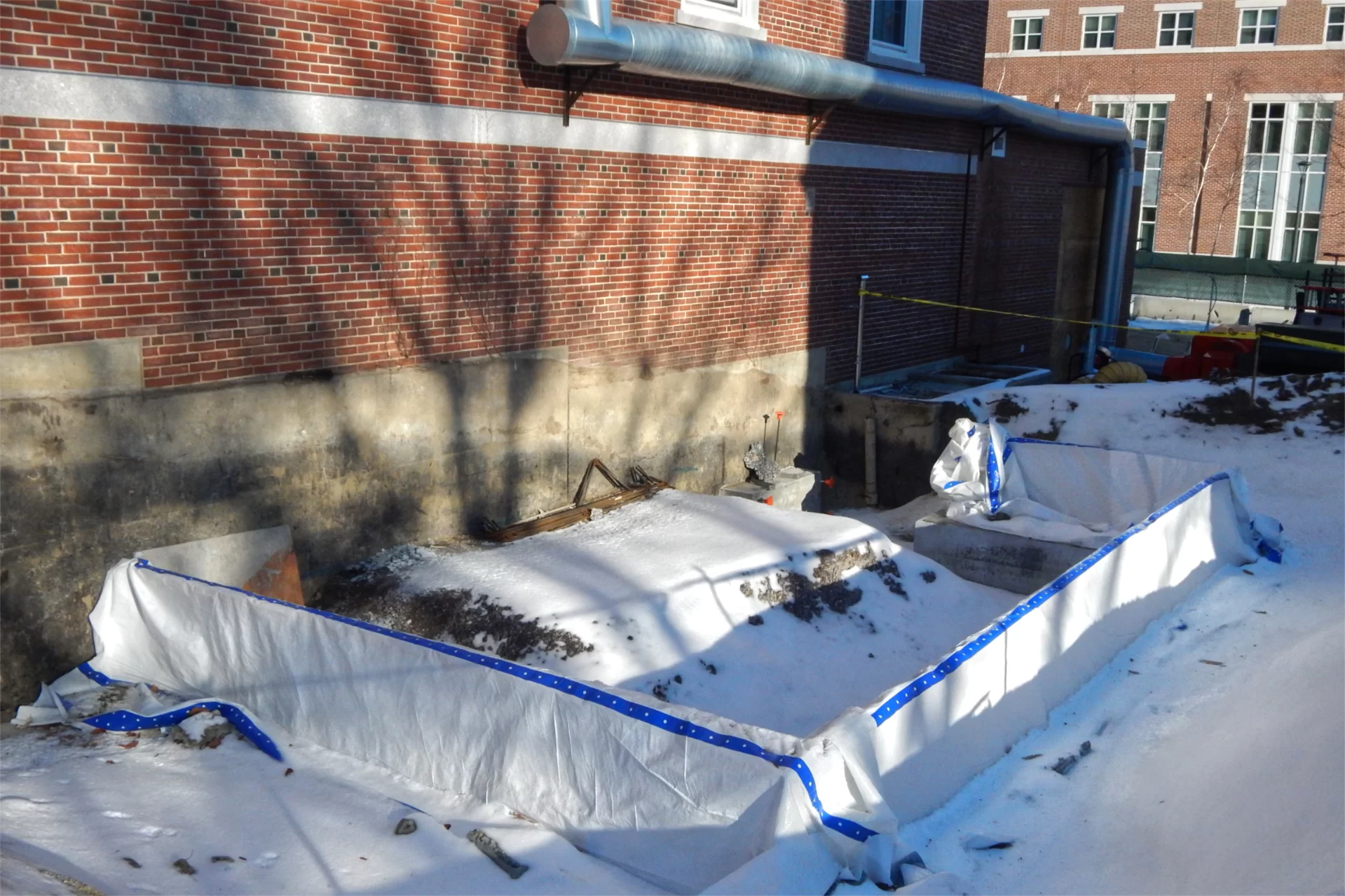 A chiller designed to supply cold water to Dana's HVAC system will be placed at this site, on the Hedge Hall side of the building, during the spring. The duct at top is bringing warmth from a portable heater inside. (Doug Hubley/Bates College)