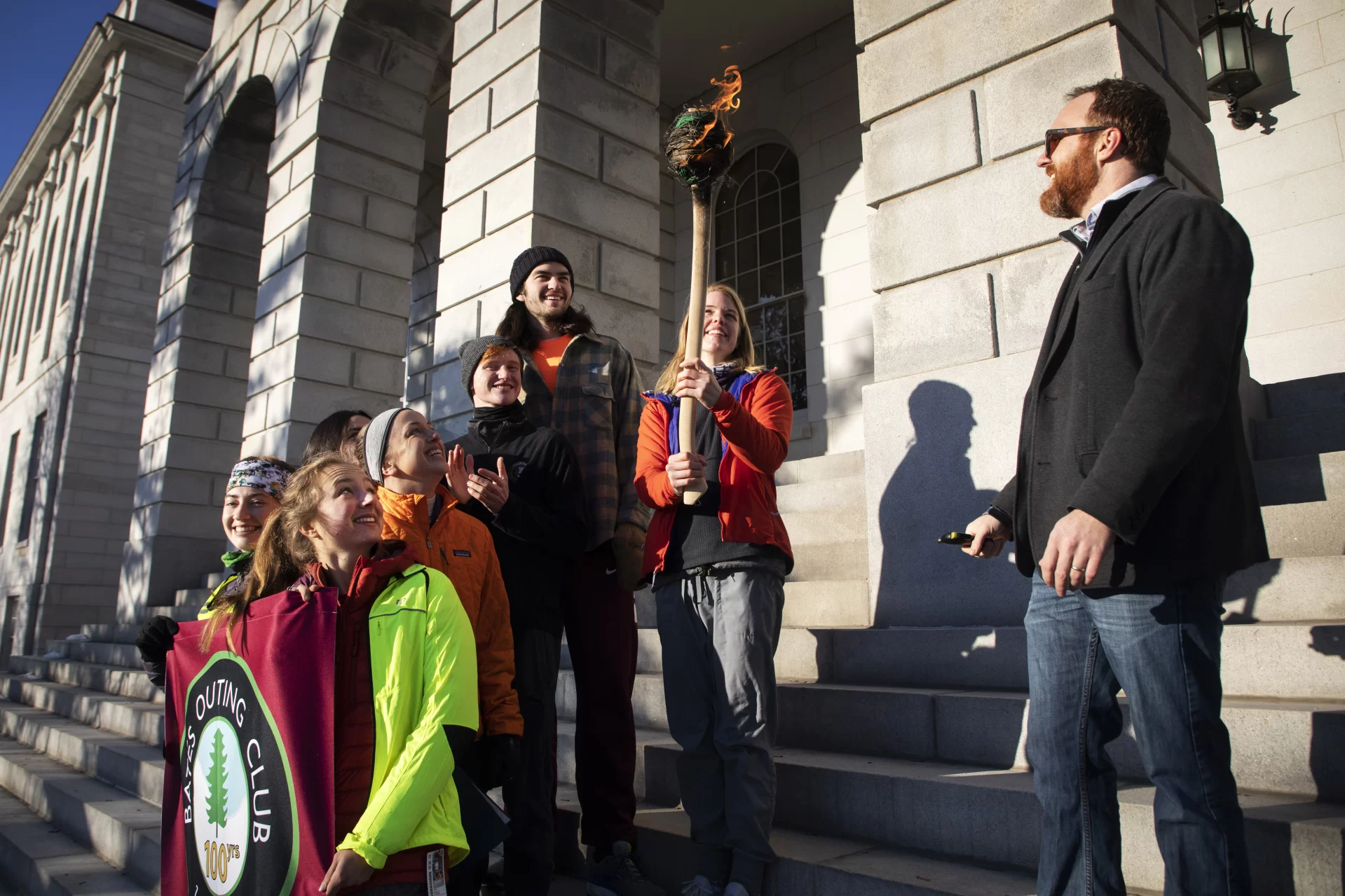 Nate Libby '07 speaks with Bates Outing Club students outside the State House on January 31, 2020. Students light a ceremonial torch and run back to Bates College to begin the Winter Carnival.