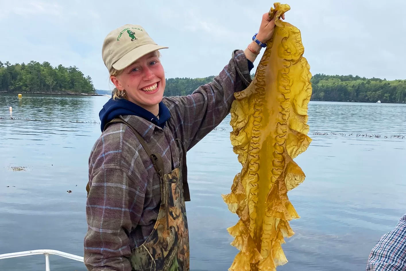 In July 2017, Essie Martin '22 brandishes a leaf of kelp while working at Maine Sea Farm, which grows kelp for harvest in Walpole, Maine. (Photograph courtesy of LIncoln Academy)