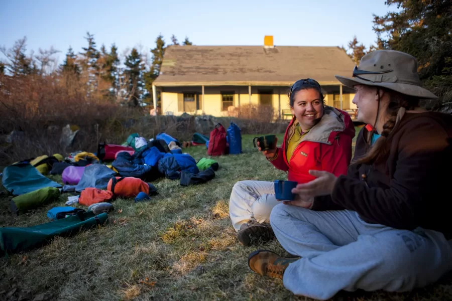 Jackie Ordemann '15 and Grace Kenney '16 share warm drinks on Little Cranberry Island during a trip with Dyk Eusden's Geology of the Maine Coast by Sea Kayak class. (Sarah Crosby/Bates College)