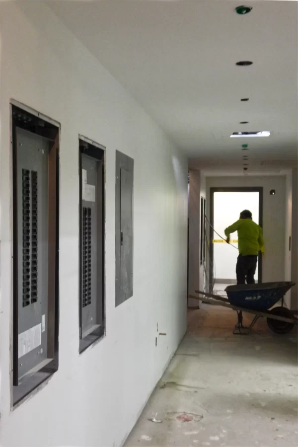 An electrician pulls cable into a first-floor breaker box, one of several in this corridor. (But do the cables ever pull back?) (Doug Hubley/Bates College)