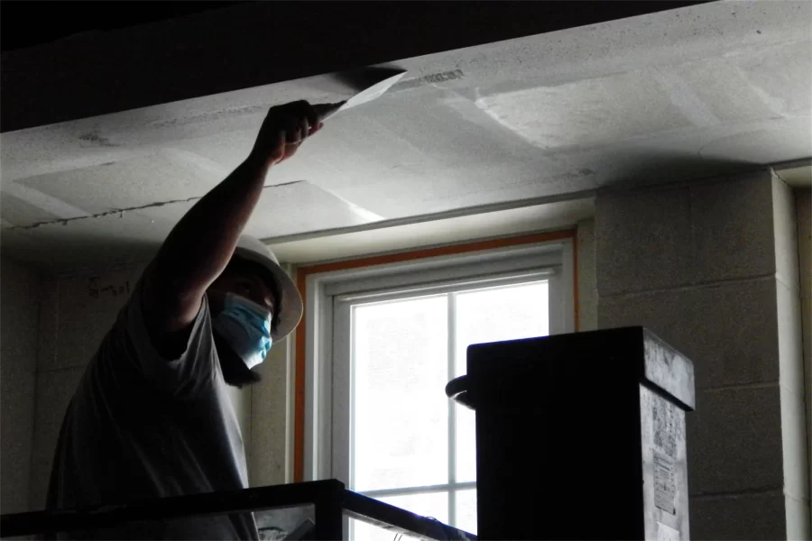A wallboard installer muds a seam over a first-floor window. (Doug Hubley/Bates College)