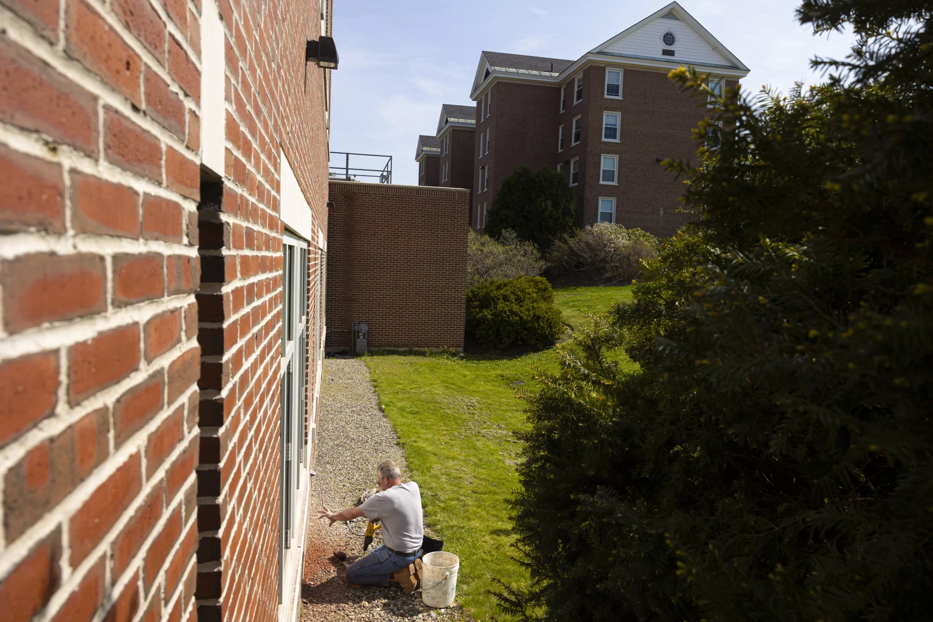 Bates mason Ronald Tardif installs the Class of 2022 Ivy Stone on the side of Pettengill Hall facing Commons. Katy Boehm ’22 of Denver, Colo., designed the stone.