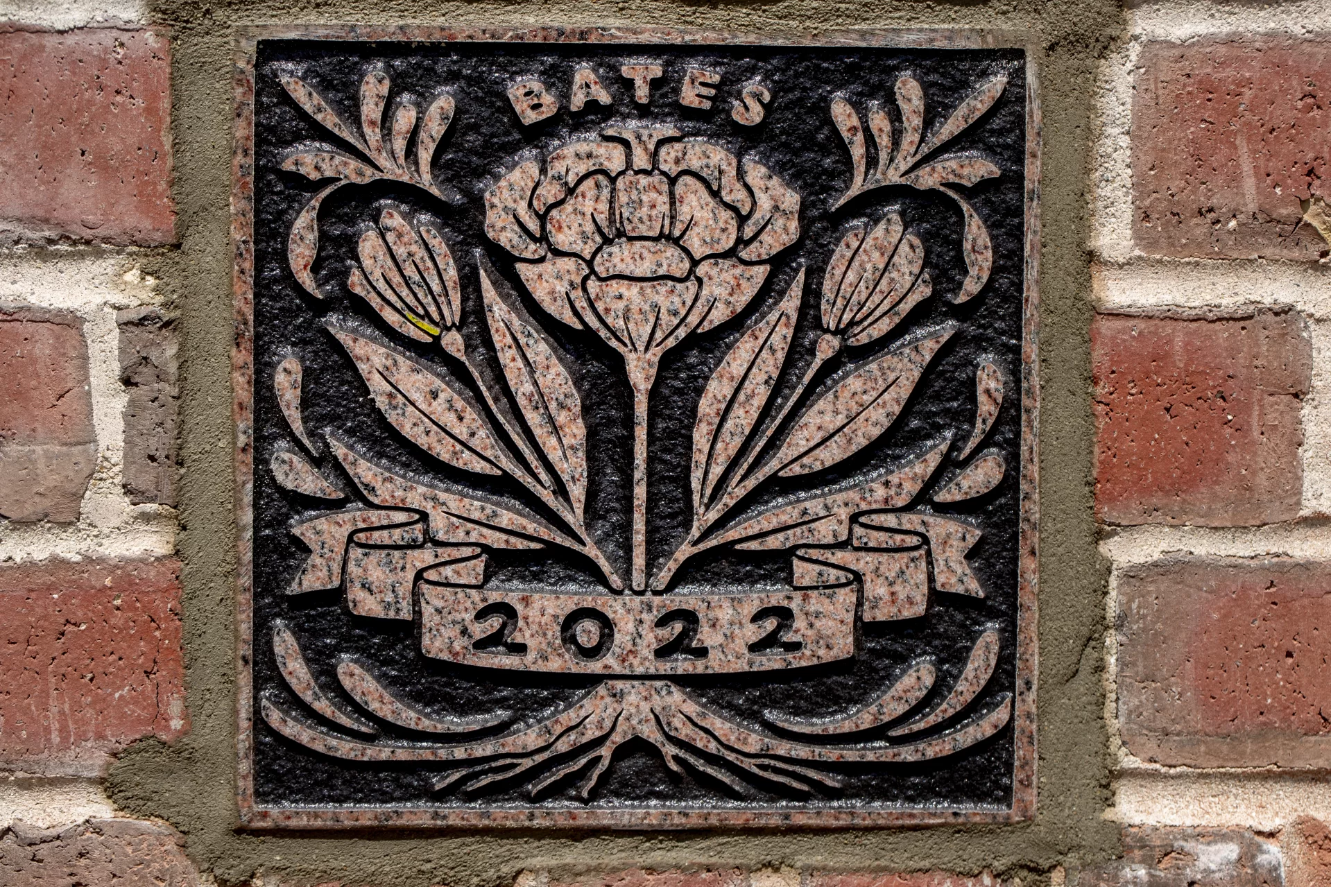 Bates mason Ronald Tardif installs the Class of 2022 Ivy Stone on the side of Pettengill Hall facing Commons. Katy Boehm ’22 of Denver, Colo., designed the stone.