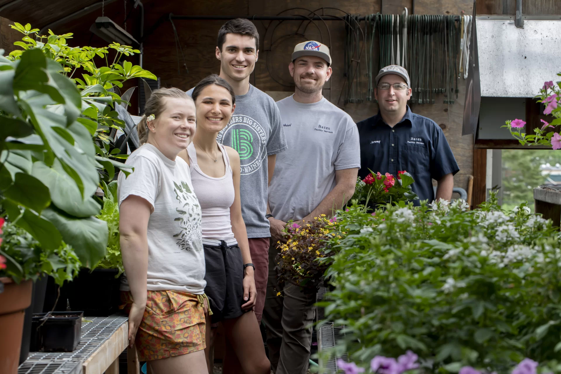 Grounds & Maintenance Lead - Horticulture Focus Jeremy Lavertu and Grounds and Maintenance Worker Jon-Michael Foley (both of Facility Services) work with three student landscape assistants in the college’s greenhouse behind Cutten Maintenance Center. They’re preparing plants for campus distribution.Students are Charlotte Collins ’22 (frog t-shirt with flowers in ear) of Woolwich, Maine, Clay Hundertmark ’22 (gray t-shirt) of Portsmouth, N.H., and Taylor Alexander ’22 (tank top) from Bethesda, Md.