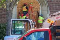 Workers for Gendron & Gendron board up Chase Hall’s main entrance on Campus Aveue prior to the demolition of its concrete stairs. (Doug Hubley/Bates College)