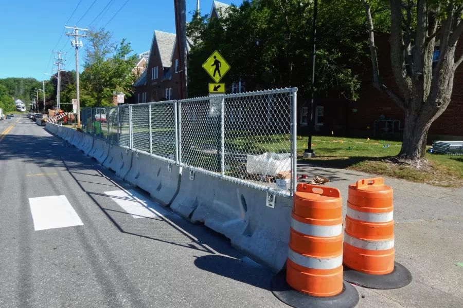 A site fence being set up around the Chase Hall construction zone on June 6. Jersey barriers are used as bases for the fence where vehicular traffic is present. (Doug Hubley/Bates College)