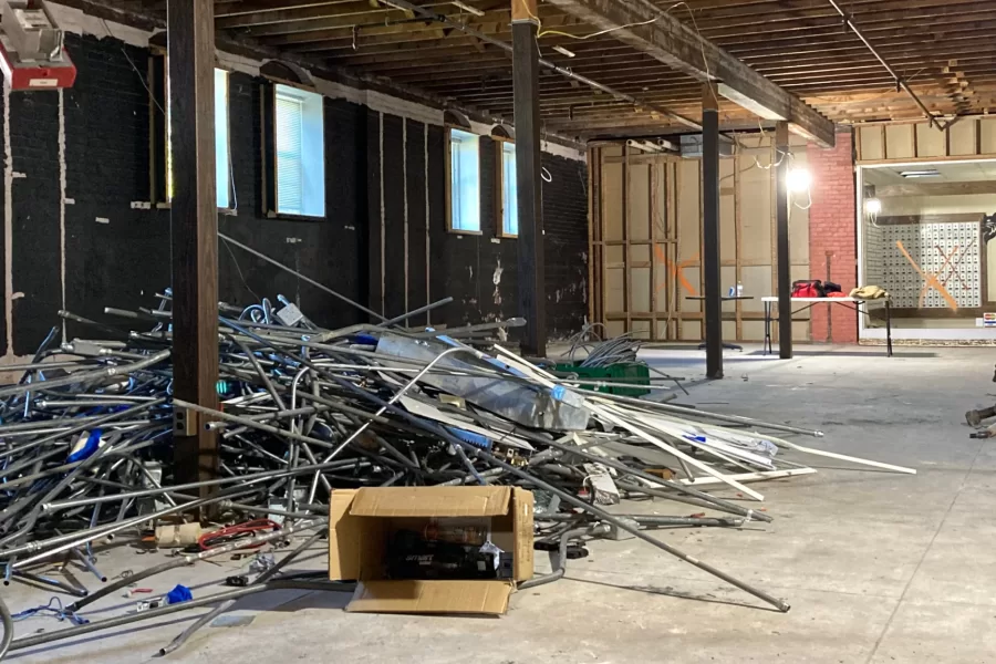 Pipes, conduits, and other demolition debris lies in a heap in the former site of the College Store in Chase Hall. Through the glass at right are long-disused student mailboxes. (Doug Hubley/Bates College)