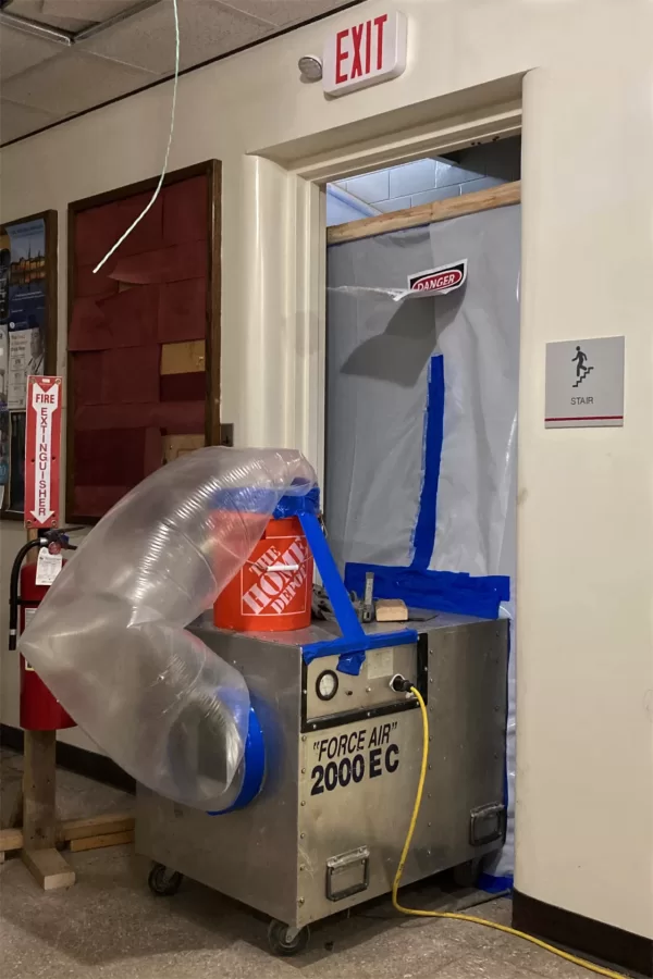 Inside the plastic in this ground-floor doorway, hazmat abatement specialists are at work on the Chase Hall stairway nearest the Kenison Gate. (Doug Hubley/Bates College)