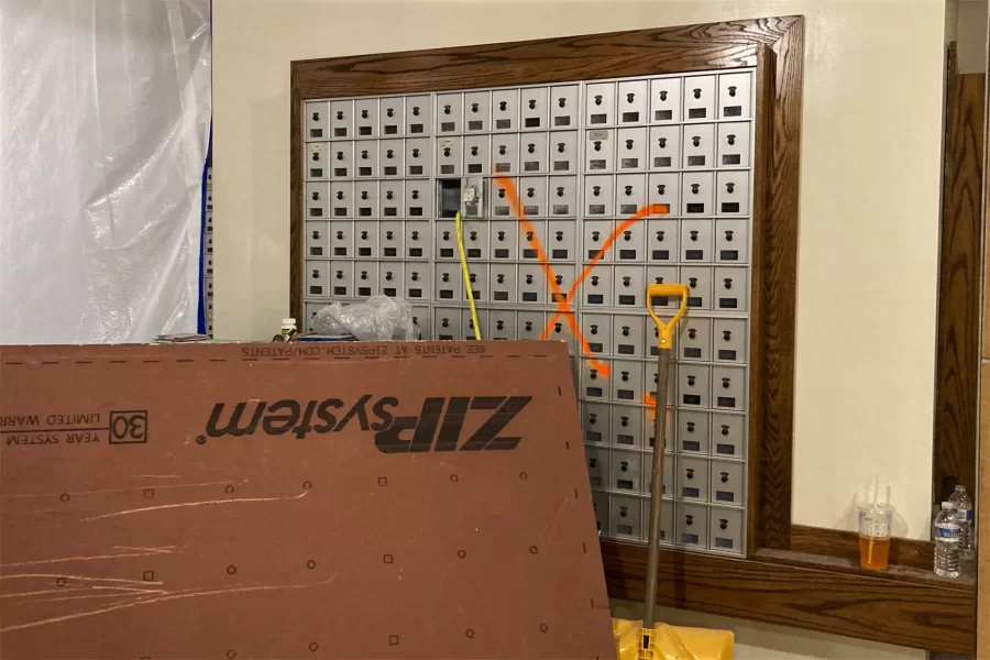 Once the use of student post-office boxes kept this spot on Chase Hall's ground floor busy. But it's now a place to park equipment and supplies as hazardous waste abatement takes place behind the wall and poly sheeting.  (Doug Hubley/Bates College)