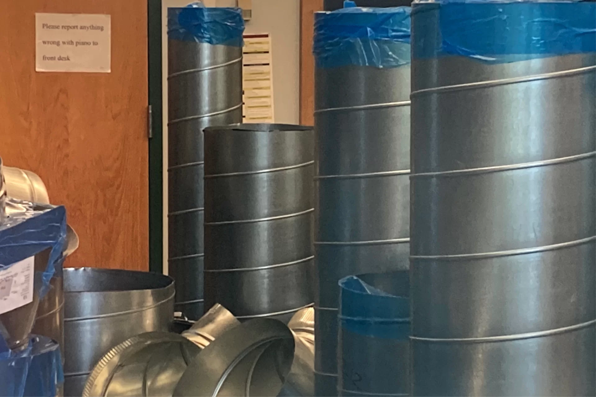 Seen through an Olin Arts Center window, new air ducts are stored in a music classroom as they await installation. (Doug Hubley/Bates College)