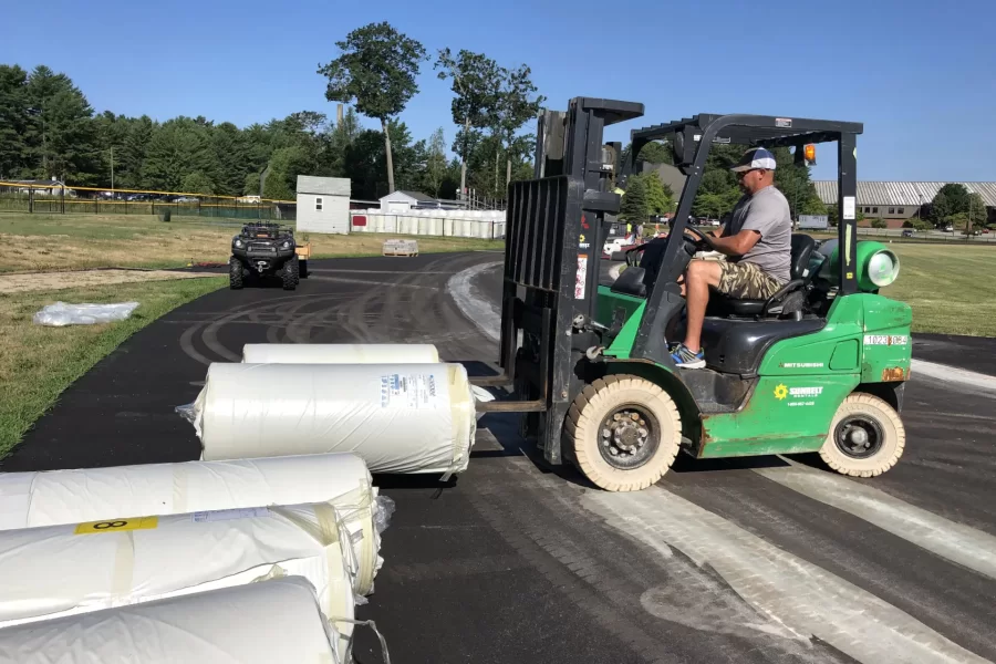 Tim Moehling of Wicked Flooring uses a forklift to move a 50-foot roll of Mondo track surface on July 28. (Jay Burns/Bates College)