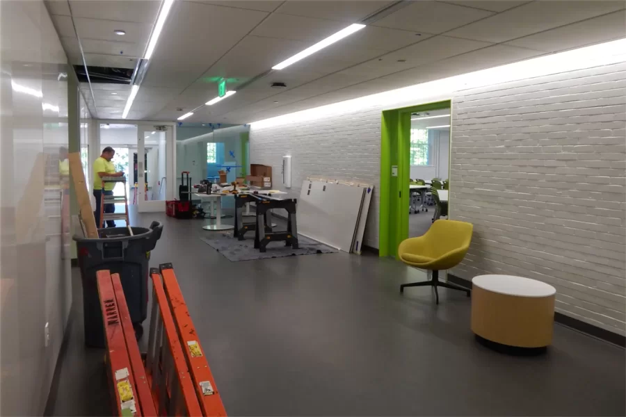 Dana Hall's second-floor lobby. The entrance at center left opens onto the Historic Quad. The workbench at center is used for cutting plastic lenses for ceiling light fixtures like the ones overhead. (Doug Hubley/Bates College)