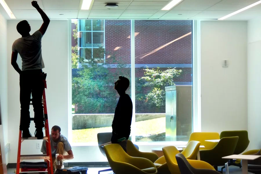 Pulling a ceiling tile into place in Dana Hall's first-floor "living room.” (Doug Hubley/Bates College)