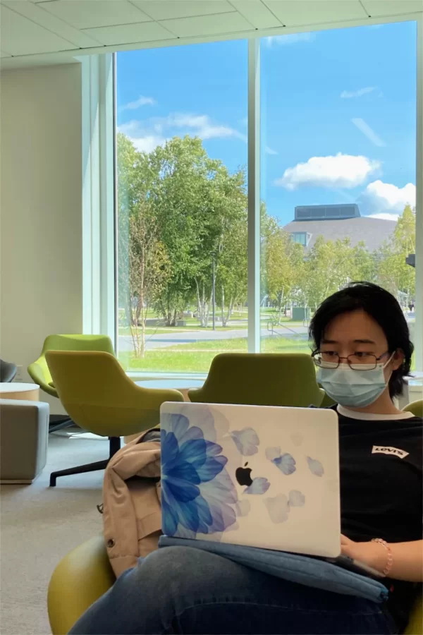 Karen Chen ’26 of Brooklyn, N.Y., studies in Dana Hall’s first-floor “living room,” which affords dramatic views of Alumni Walk and Commons. (Doug Hubley/Bates College)