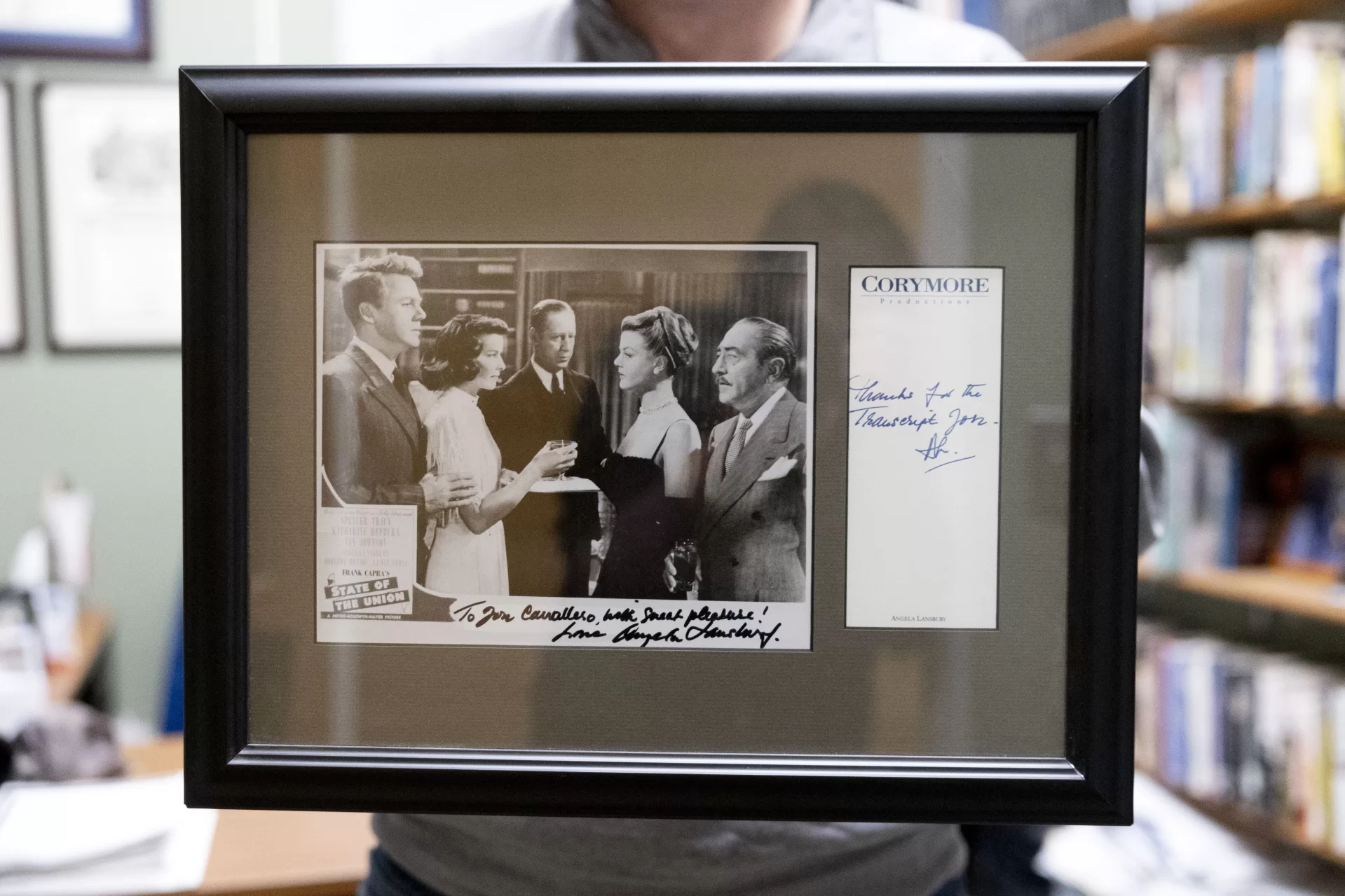 Associate Professor of Rhetoric, Film, and Screen Studies Jon Cavallero poses in his Pettigrew Hall office with his framed photograph and autographs from Angela Lansbury, whom he interviewed by phone for his master’s thesis and inspired him to reach for the stars.