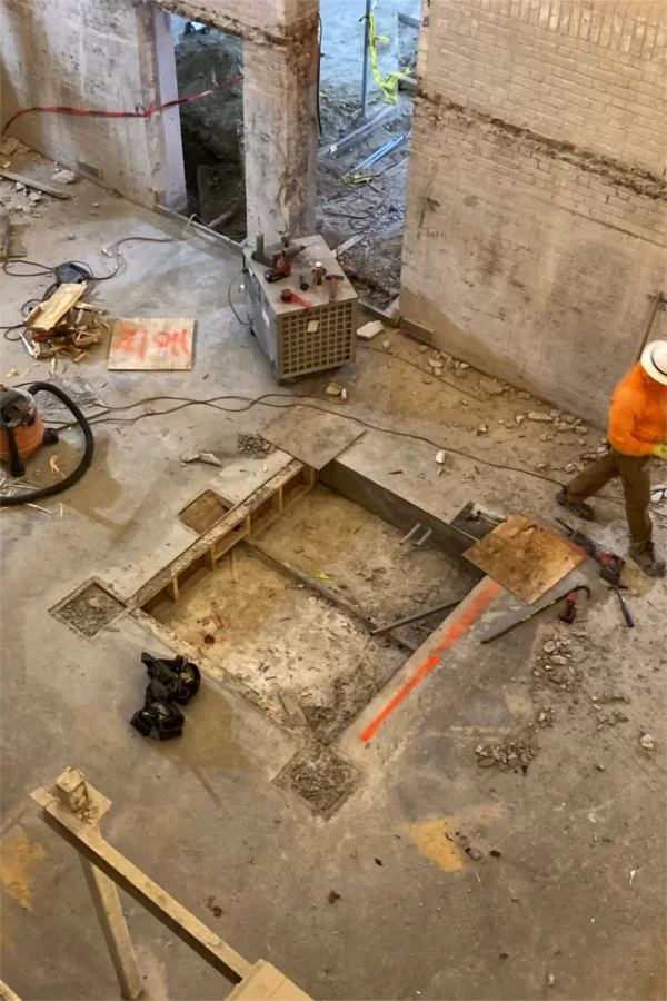 The square pit will be the base for a new Chase Hall elevator. The sign that says "Hole" covers the footing for one of the steel columns that will support new stairs and floors in this space adjacent to the once and future Office of Intercultural Education (out of the frame at left). (Doug Hubley/Bates College)