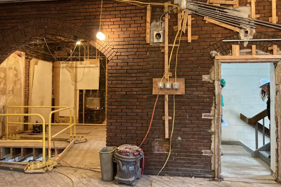 The east end of Chase Hall Lounge. The arch and surrounding bricks will be left exposed, but sheetrock will cover the righthand half of the wall. Peeping through the doorway are Bates Project Manager Kristi Mynhier and a project engineer. (Doug Hubley/Bates College)