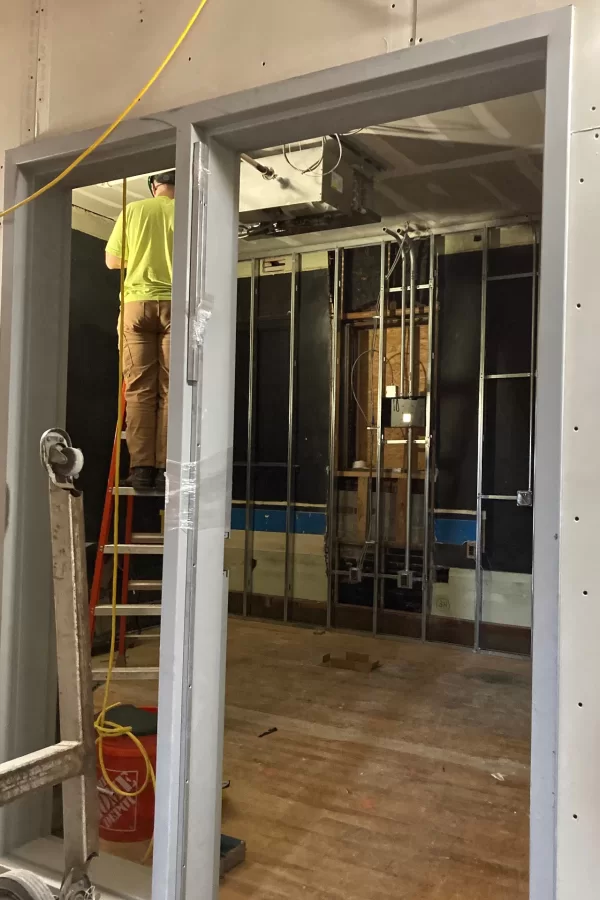 A technician connects a new HVAC fan-coil unit in a second-floor office in Chase Hall. Mechanical, electrical, and plumbing work — aka MEP — is a high priority in the Chase Hall renovation these days. (Doug Hubley/Bates College)