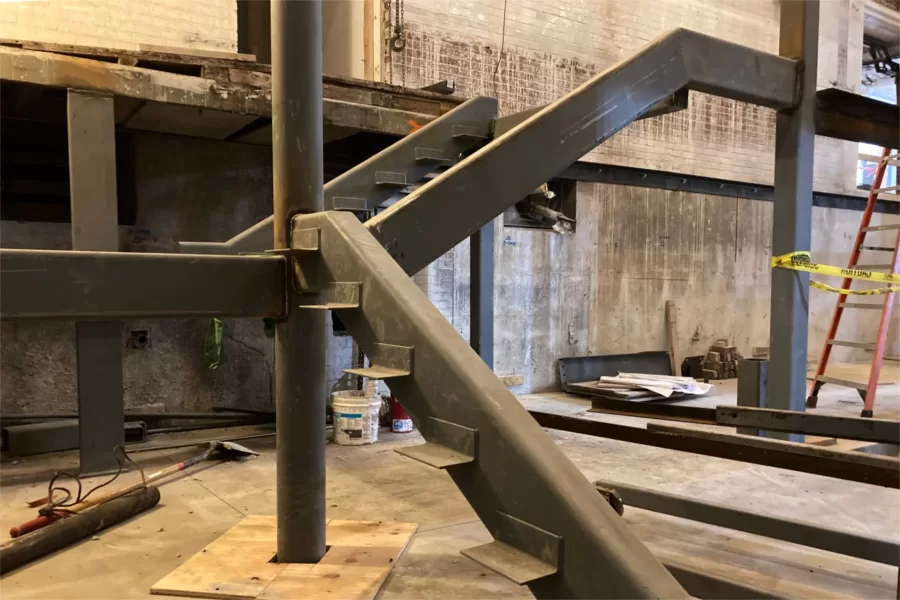 This ground-level view of new structural steel for Chase Hall’s central stair shows brackets that will support stair treads. Note the distance between the floor and the first stair landing: one-half level. (Doug Hubley/Bates College)