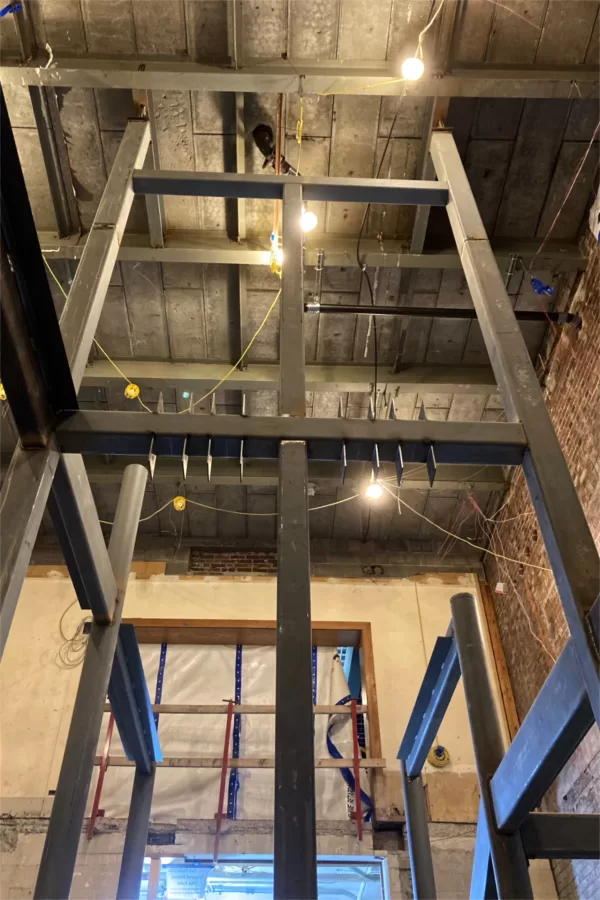 Located in the 1978 addition to Chase Hall — you can tell from, among other clues, the precast  concrete slabs overhead — this newly placed structural steel will support the central stair. (Doug Hubley/Bates College)