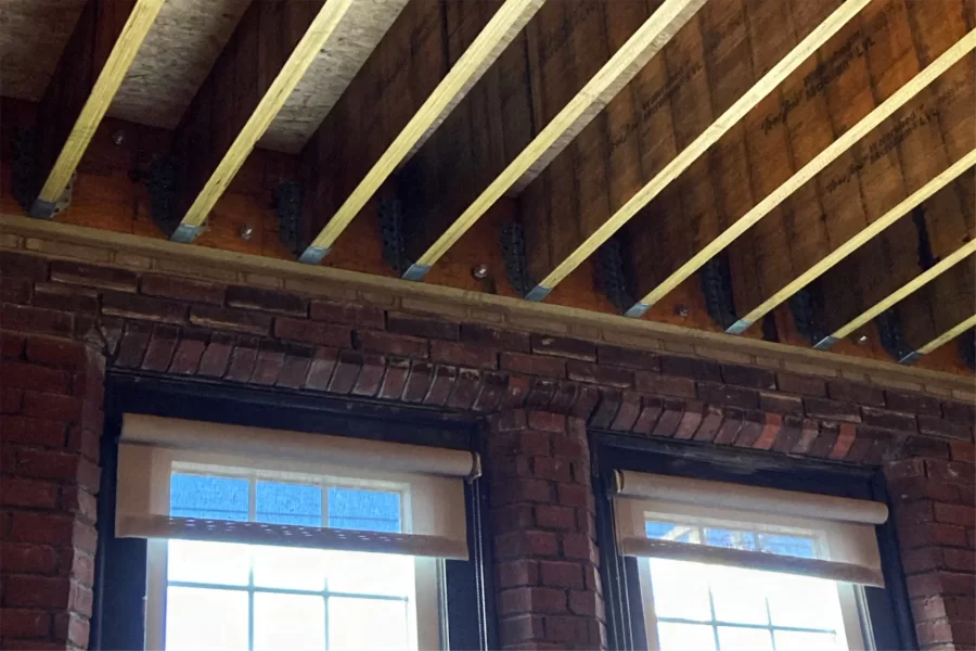 New joists and floorboards are mated to a new ledger board and masonry in this decking above Chase Hall Lounge. A large section of the old floor was replaced because of moisture damage. (Doug Hubley/Bates College)