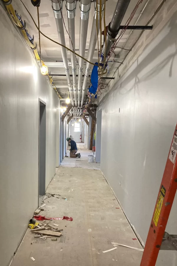 Finishing wallboard and subflooring seams in the second-floor corridor in Chase Hall. (Doug Hubley/Bates College)