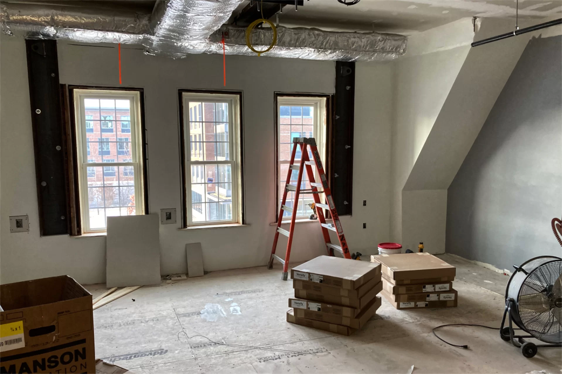 Just a few weeks ago there was a gaping hole in the floor adjacent to the windows in this second-floor lounge. The elaborate repair involving new masonry and joist extensions is now hidden and few people will ever give it a thought. But the dark steel supports that bracket the windows will remain exposed. (Doug Hubley/Bates College)