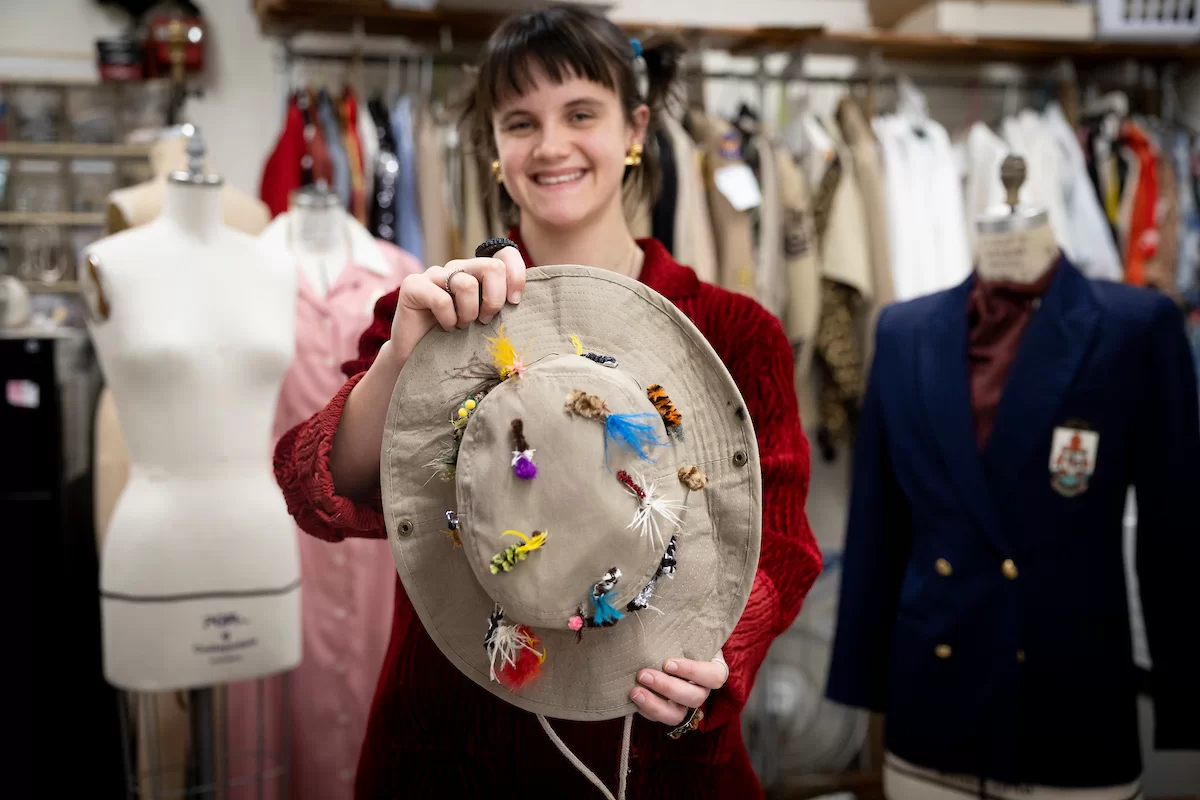 Carol Farrell, supervisor of the Bates Theater Department’s costume shop, and costume designer for the theater department’s upcoming production of Shakespeare’s “Much Ado About Nothing,” is leaning on for a neat costume change from 16th-century Italy, to Bar Harbor, Maine, in 1945.

Here she works on Feb. 2, 2023, with Adelle Welch ’25 (garnet sweater) of Livingston, Mont., a double major in and earth and climate science and dance and Jenna Perry ’25 (gray sweater), a psychology major from Las Vegas.

Welch designed a bucket hat with lures for the production.