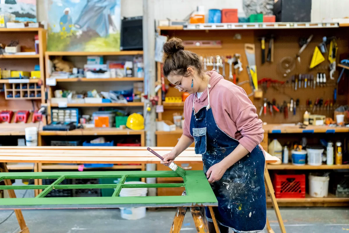 Justin Moriarty, technical Director for Theater and Dance, directs students Natalia Jacobs '26 of Amherst, Mass., (in downstairs shop) and Gideon Berrie '26  of New York City (on the Schaeffer Theatre stage)  in building and painting sets in the shop and on the stage of Schaeffer Theater with the assistance of Aidan McDowell on February 14, 2023.