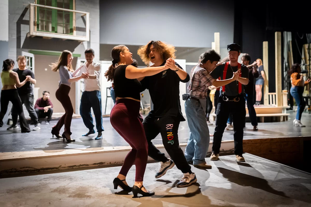 Mia Bernstein ’23 of Bedford, Mass., teaches a dance to actors in Shakespeare’s “Much Ado About Nothing” directed by Assistant Professor of Theater Tim Dugan on the stage of Schaeffer Theatre on Feb. 16, 2023. Stage Manager Lucie Green ’23 of Pittsburgh is also shown in action, seated and moving throughout the theater seats.