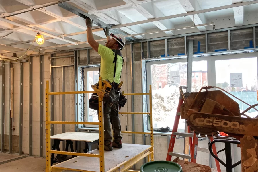 Fitting a ceiling channel for wall studs in a section of Chase Hall’s ground floor that will house Student Affairs offices. The windows, offering views of the Library Quad, are new. (Doug Hubley/Bates College)