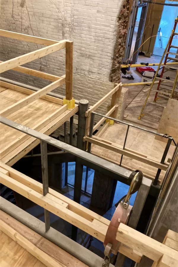 This image provides some sense of how the central stair will function. Taken from the top level, it shows a walkway one-half level below (and, in shadow, the ground level access). The doorway at upper right leads to stairs exiting the building — that blue glow. (Doug Hubley/Bates College)
