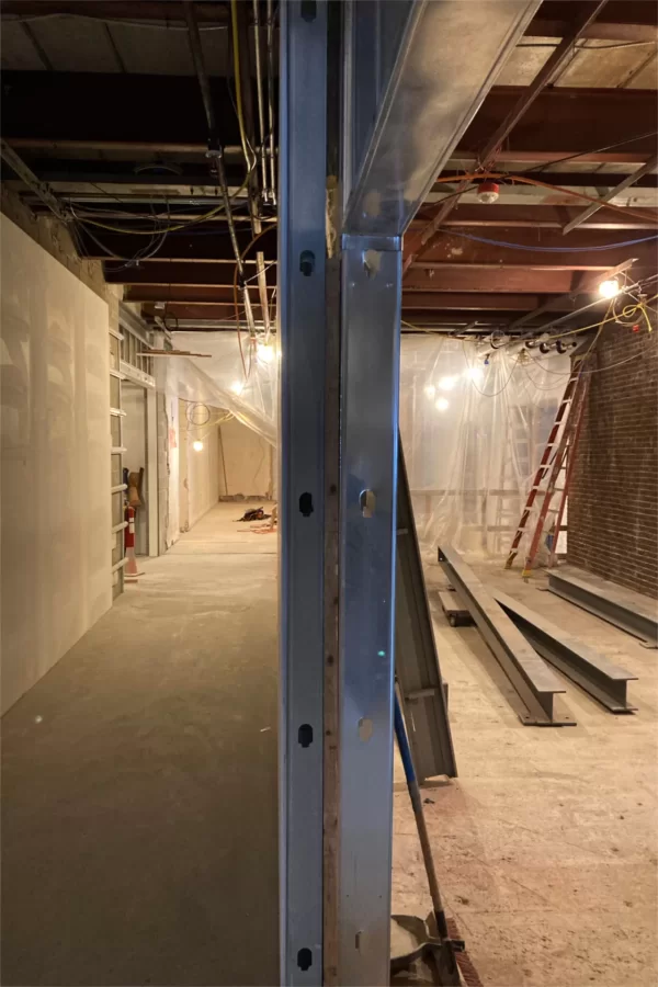 Bisected by metal wall studs, this view faces the central stair and the future reception area for the Office of Multicultural Education. At right is a mechanical room that will house air-handling equipment that will rest on the girders. (Doug Hubley/Bates College)