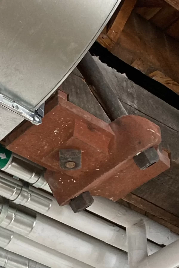 One objective of the current Chase Hall renovation is to reveal architectural features, especially in the century-old original section, that were concealed by previous makeovers. Here, bolted to a ceiling beam in the Purposeful Work suite, is an anchor for metal truss rods. (Doug Hubley/Bates College)