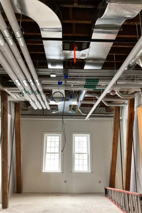 In some sections of the renovated Chase Hall, like this common space in the Purposeful Work suite, overhead utilities will be embellished with “clouds” — sections of ceiling tile with gaps around the edges. (Doug Hubley/Bates College)