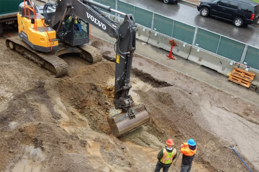 As two Gendron & Gendron employees look on, an excavator contours soil for a ramp that will lead to Chase Hall’s main Campus Avenue entrance. (Doug Hubley/Bates College)