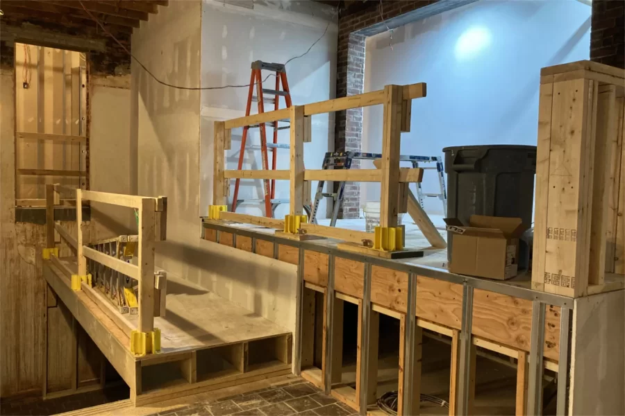 The Overnook, a feature in Chase Hall’s first-floor lobby, is shown on April 25. The temporary platform at left was built to provide footing for workers erecting the corner wall. (Doug Hubley/Bates College)