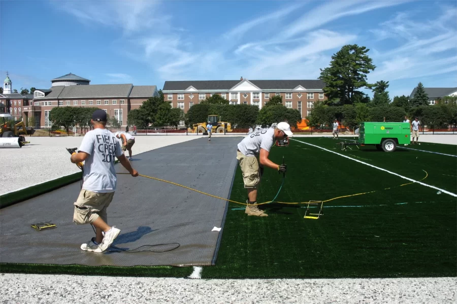 In this 2010 image, workers prepare to flip another strip of FieldTurf, at left, into place. (Gabrielle Otto '11 for Bates College)