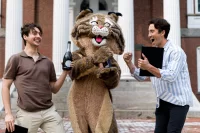 The Bates Bobcat (played by BCO writer Freddie Wright) tours Lake Andrews and the historic Quad with BCO designer Kirsten Burns. On left, in brown shirt, William Spencer Orto Symmans ’23, whose neuroscience thesis is titled “ A Data-Drive Taxonomy of Olfactory System Principal Neurons.” On right, in striped shirt, Evan Koch ’23, whose neuroscience thesis (adviser: Jason Castro) is titled “A Comparative Analysis of Gene Expression in the Dorsolateral Prefrontal Cortex of Autistic Individuals Across Age and Sex.”