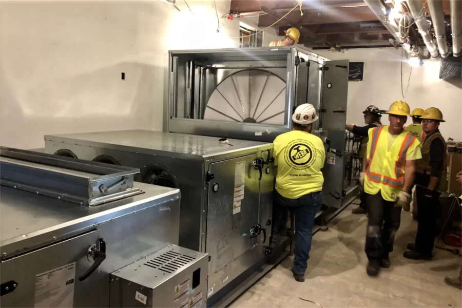 Riggers and engineers attend to components of Chase Hall’s new energy recovery ventilator, newly loaded into the building on May 17, 2023. (Jay Burns/Bates College)