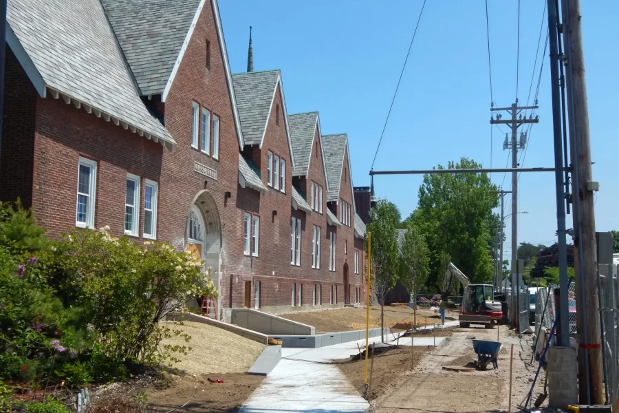 Chase Hall seen from the Kenison Gate on May 31, 2023. Twin ramps converge from the sidewalk toward the Chase entrance. Note the new loam and trees, and the darker-gray bench seating. (Doug Hubley/Bates College)