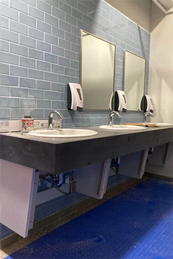 Sinks, mirrors, and soap dispensers have been installed in a new first-floor rest room in Chase Hall. (Doug Hubley/Bates College)