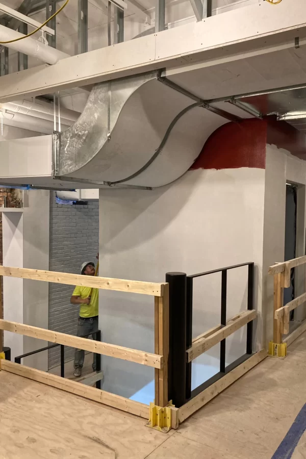 An air duct forms a graceful curve next to the elevator shaft in the Central Stair. Note the red paint, which will soon coat the entire shaft. (Doug Hubley/Bates College)