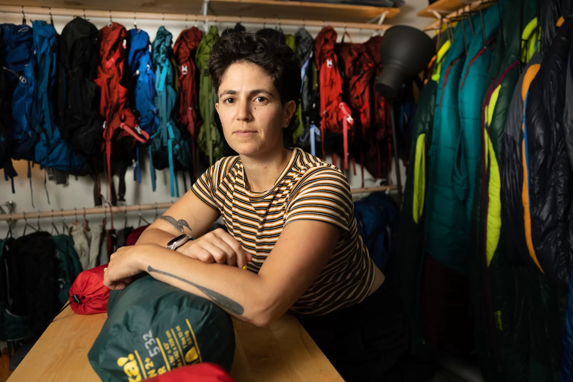 In the basement of Portland’s Equality Community Center, Portland’s newest gear library lacks the store-front appeal of the many outdoor retail shops in a state famous for its outdoor recreation. But one step inside Kindling Collective during its open house on June 10 and the orange and pink walls, the sound of laughter, and the mini outdoor-gear lessons breaking out spoke of a warm, welcoming community and, most of all: joy. Kindling Collective, a gear library focused on the queer community, was founded this spring by business partners, spouses and outdoor enthusiasts Hallie Herz ‘11 (wearing striped shirt) and Eva Fury in an effort to help the LGBTQ+ community access the outdoors in a safe, fulfilling and affordable way. The tiny 400-square-foot space welcome everyone, though it's focused on helping queer people specifically feel welcome, empowered and inspired. Focusing on joy, Hertz said, is central to their mission. Hertz and Fury were photographed at 15 Casco St. on June 15, 2023.